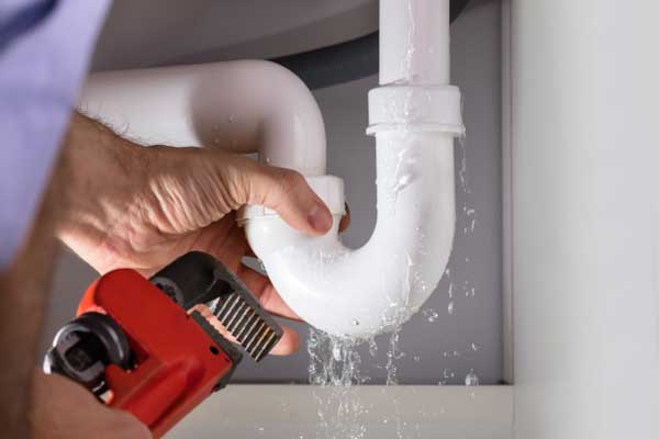 Close Up Of Male Plumber Fixing White Sink Pipe With Adjustable Wrench