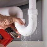 Close Up Of Male Plumber Fixing White Sink Pipe With Adjustable Wrench